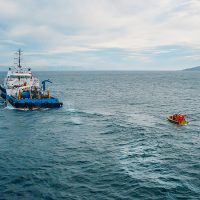 Industrial seismic ship vessel and orange boat in sea. Industrial offshore working and searching for oil in ocean